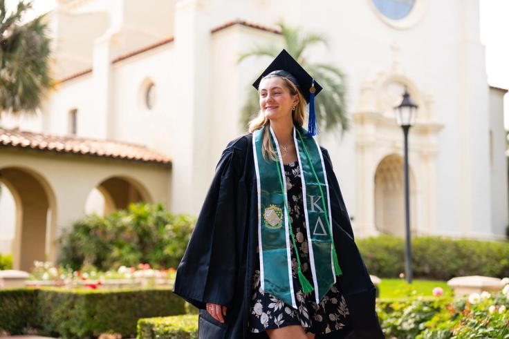 Caroline Hutchinson in graduation regalia on Rollins campus.