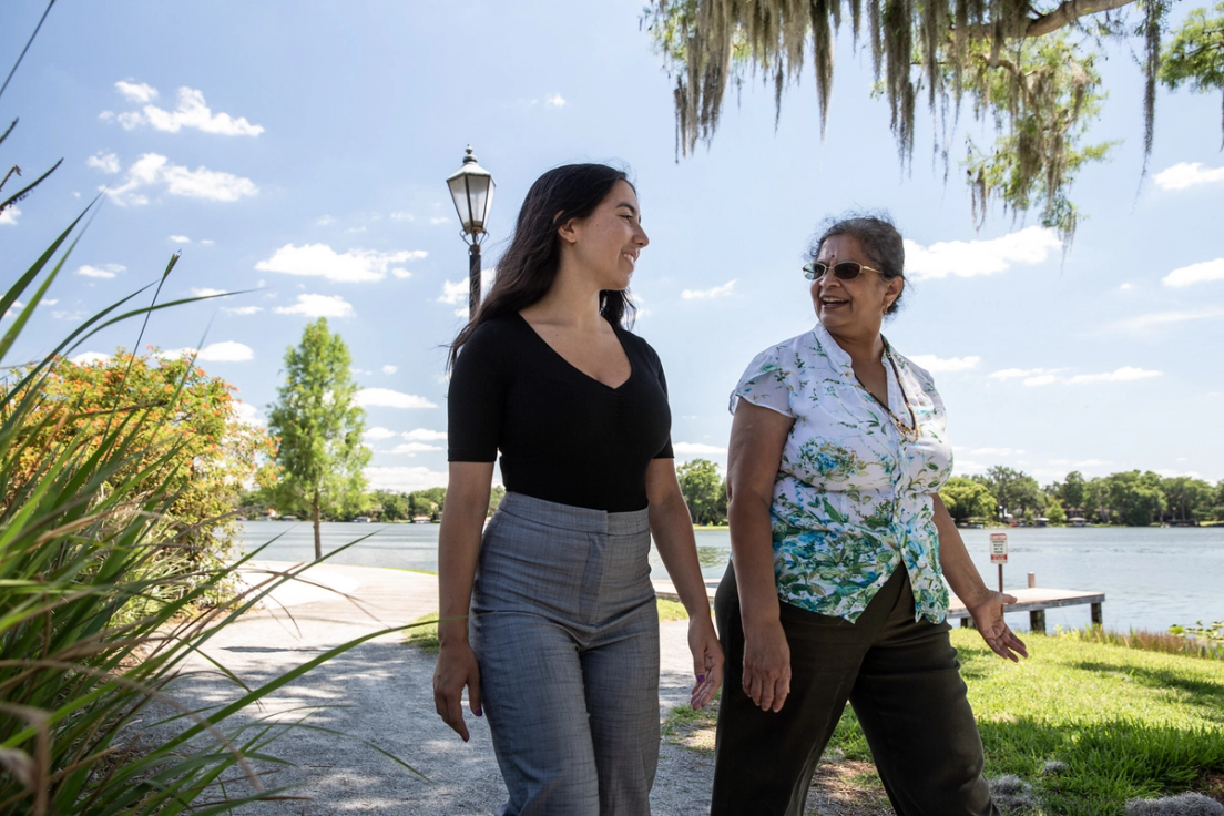 Cara Daza and Jayashree Shivamoggi walking together near the lakeside on campus.