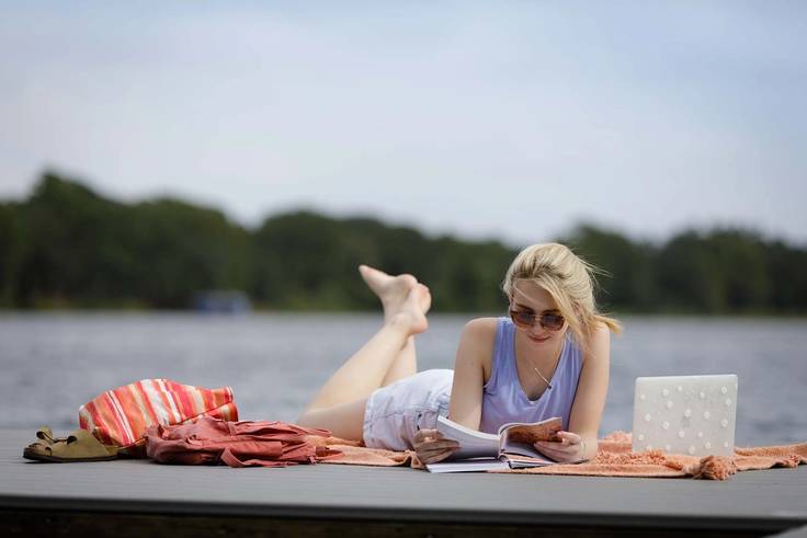 A student reads a book at the Rollins dock