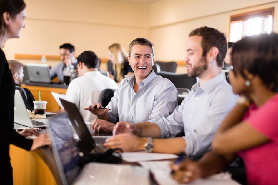 A group of business administration students laugh together in the classroom. 