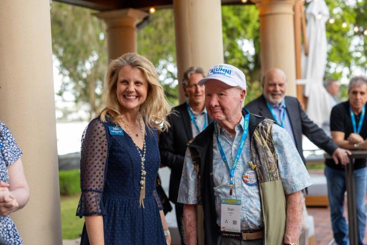 President Brooke Barnett and alumni Stan Rudd standing together under an outdoor awning.