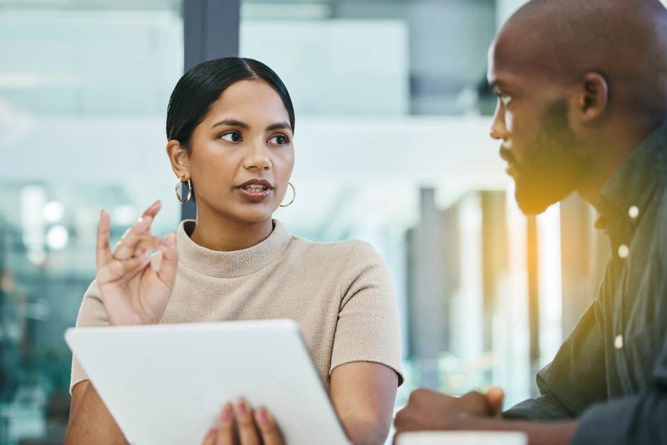 Two communication professionals discuss a campaign in a conference room.