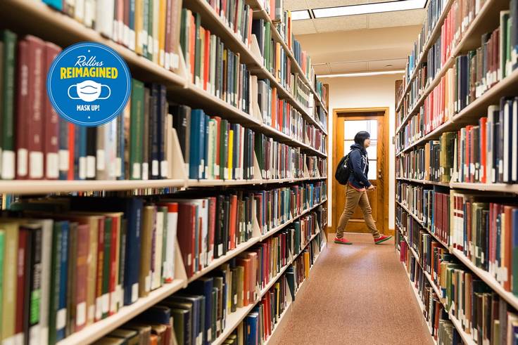Student pictured among rows of books in Olin Library.