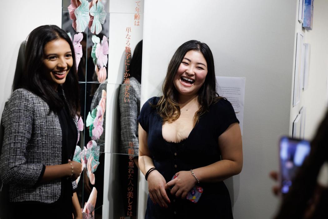 Two students pose near their art work in a gallery.