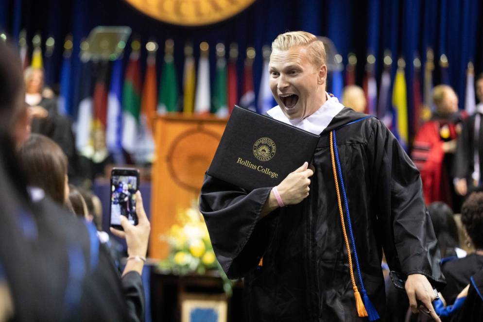 A student poses with their diploma.