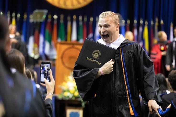 A student poses with their diploma.