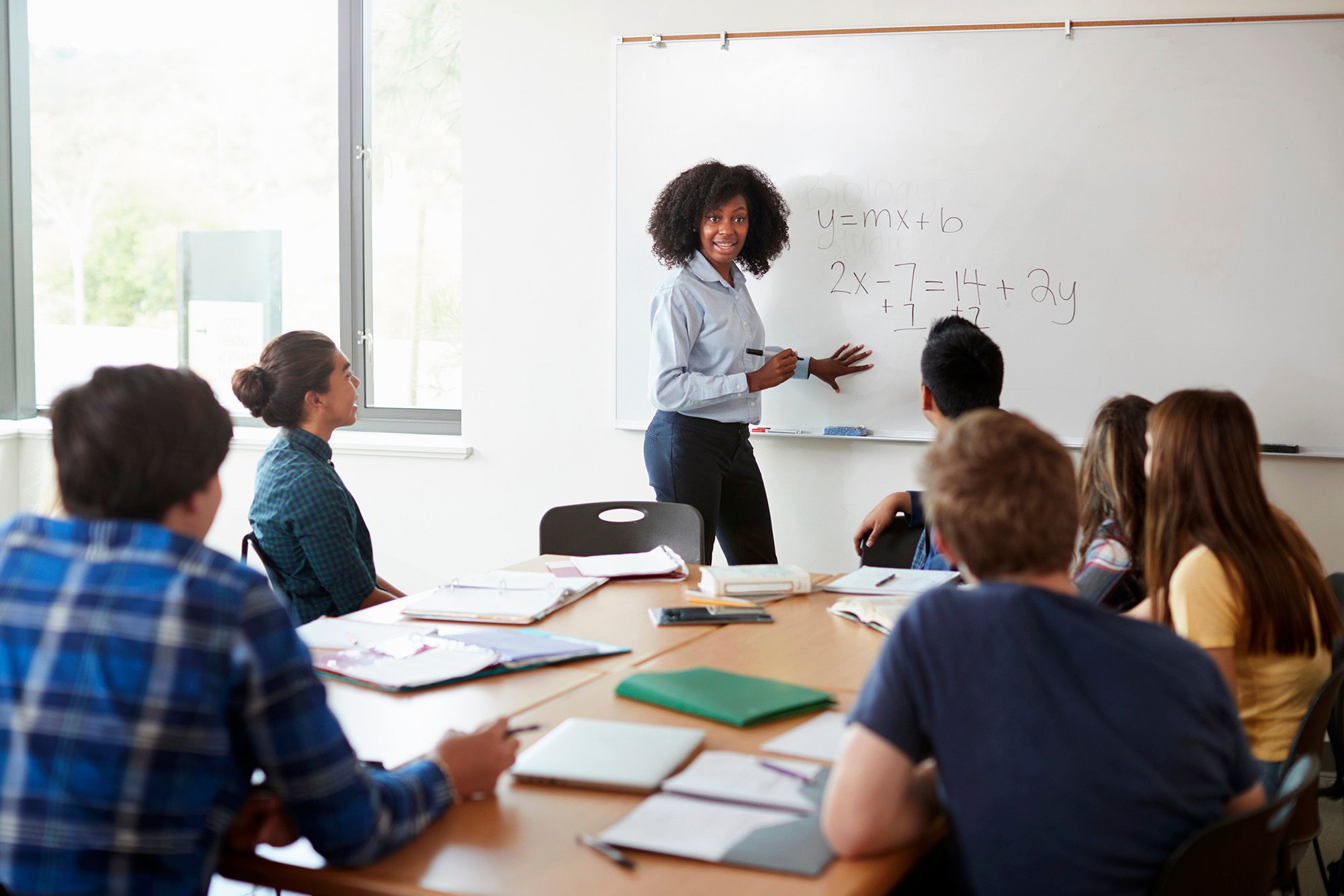 A math teacher works through a math problem on a whiteboard during class.