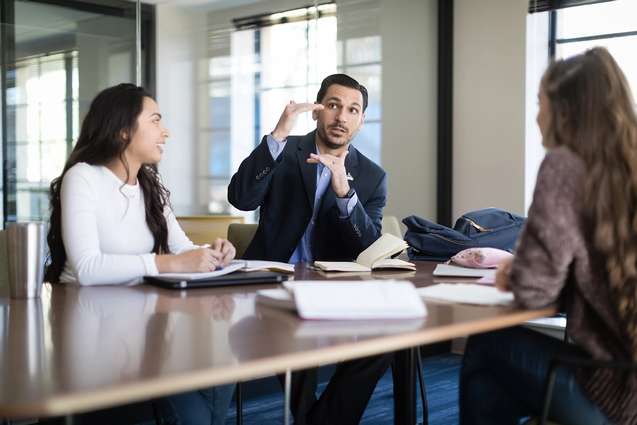 The business advising director helping two students in Kathleen W. Rollins Hall.