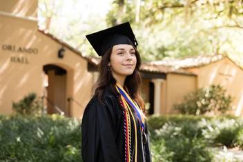 Karina Barbesino ’19 dressed in graduation regalia on campus.