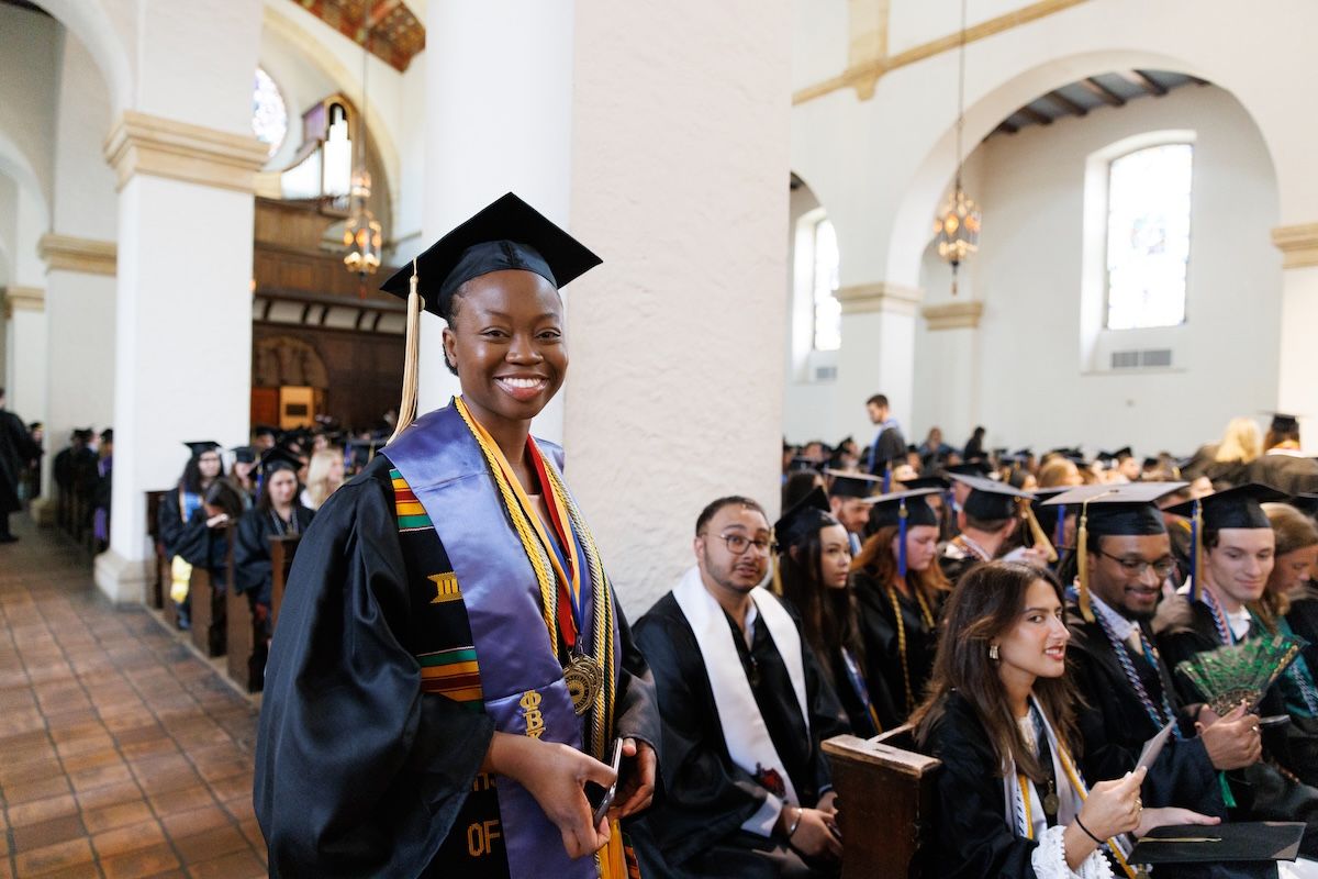 A Rollins student in cap and gown prepares for commencement.