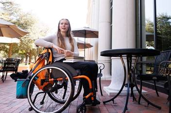 girl with long hair in wheel chair at outdoor table