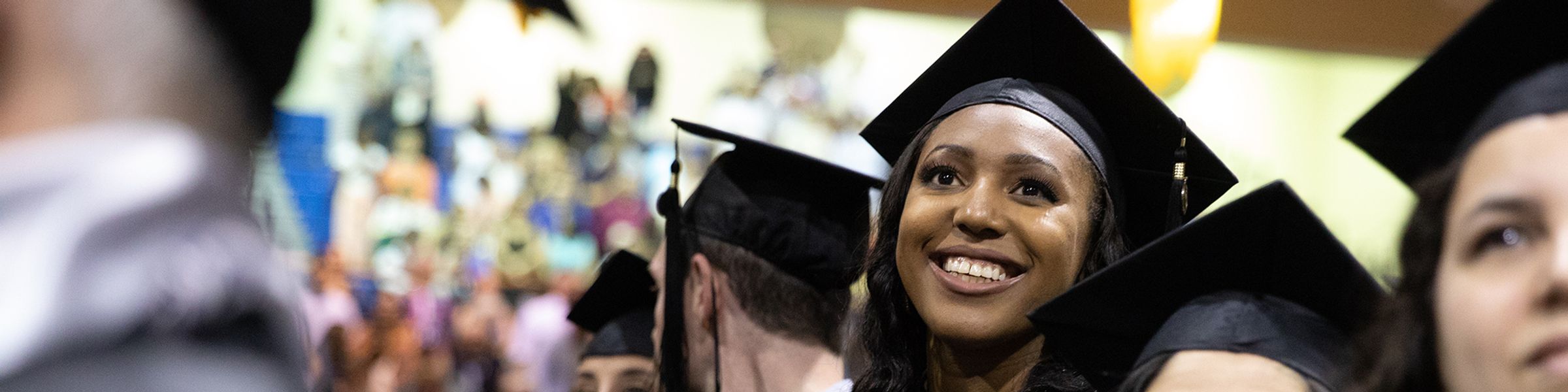 An adult graduate student in graduation cap and gown ready to earn their degree.