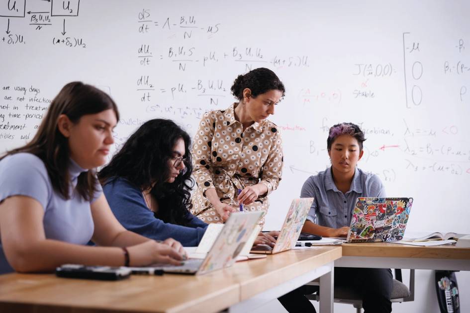 A professor works one on one with a student in class.