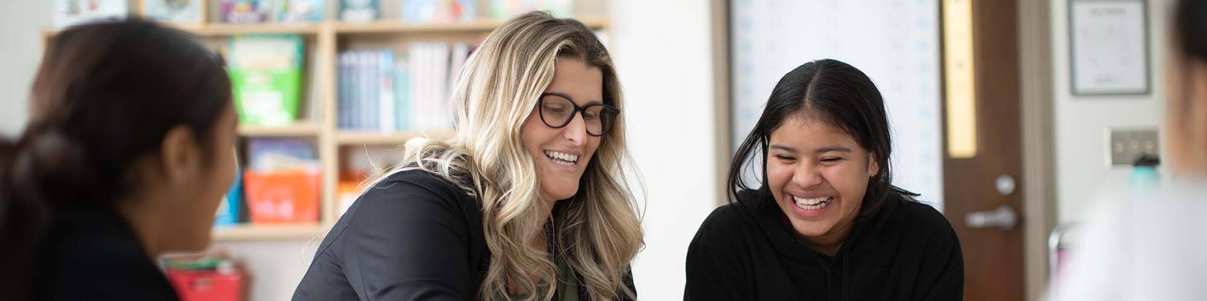 A teacher and student laugh together