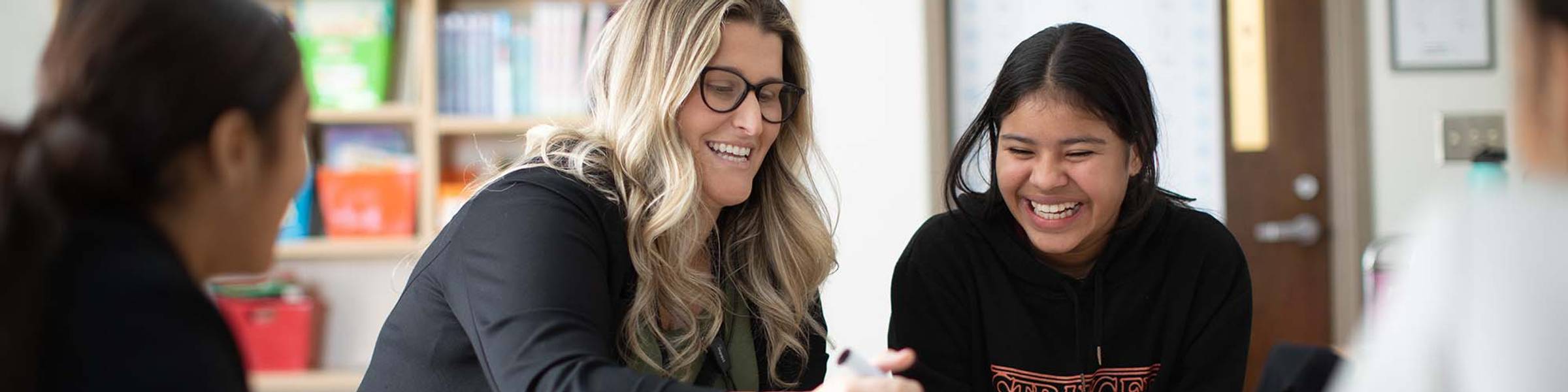 An elementary school teacher helps a group of students with a lesson.