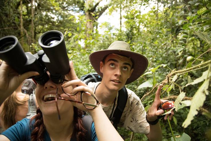 Students using binoculars to spy flora and fauna in a Costa Rican rainforest.