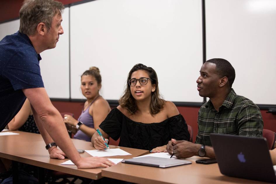 A Latin American & Caribbean professor speaks to two students about their project in class.