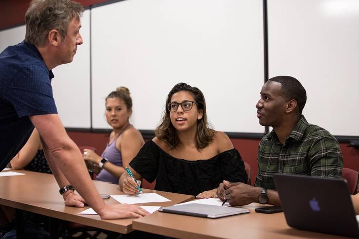 A Latin American & Caribbean professor speaks to two students about their project in class.