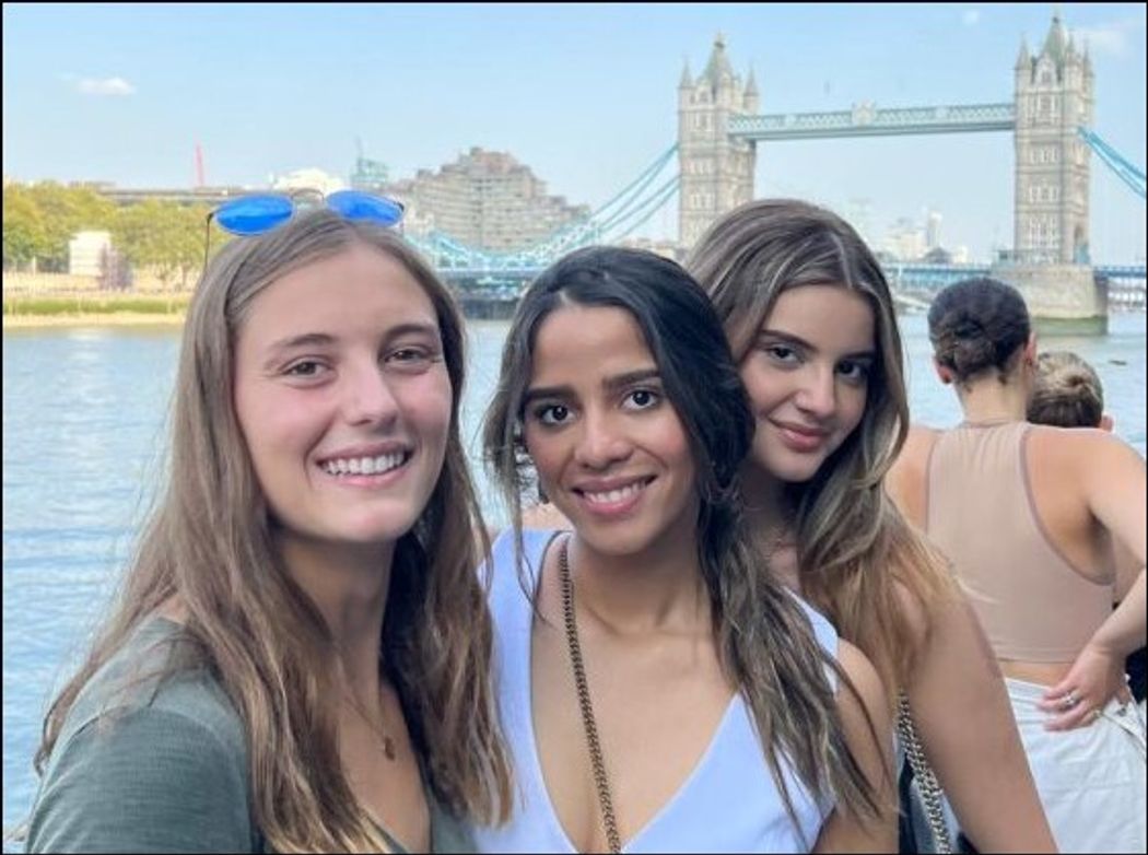 Students smiling to camera with the London Bridge behind them.