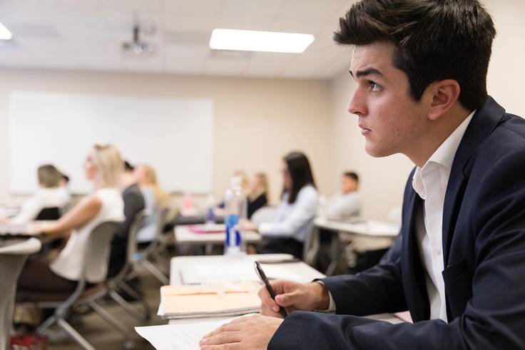International business classroom at Rollins, close up of a student listening to the professor lecture.