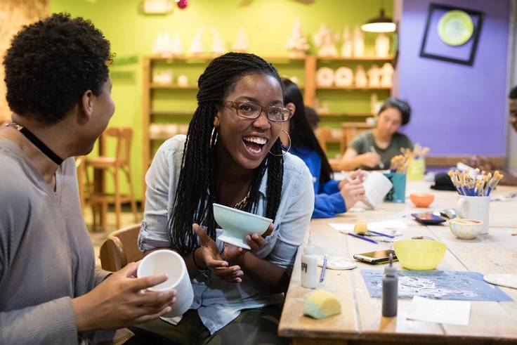 A student laughs with a classmate at a coffee shop.