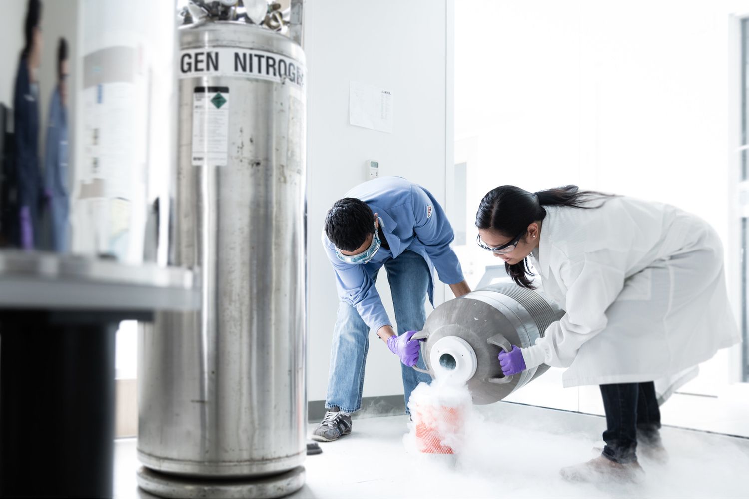 A chemistry professor and a student pour liquid nitrogen into a container during an experiment.