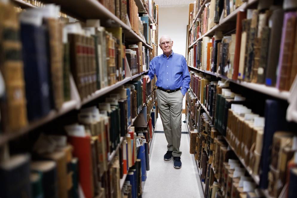 Jake Lane stands amid a row of library shelves. 