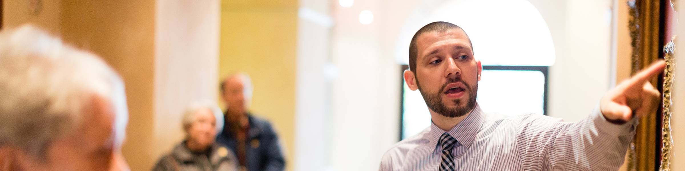 A museum curator shows a piece of artwork to a group of art enthusiasts.