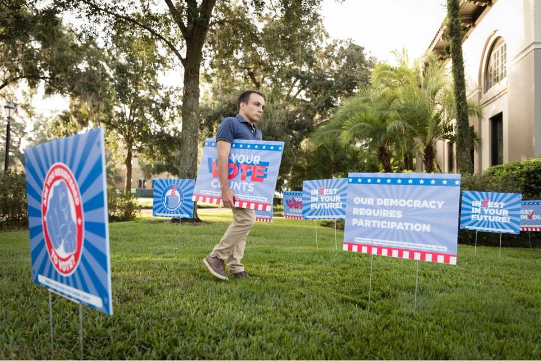 A student planting yard signs for the Democracy Project.