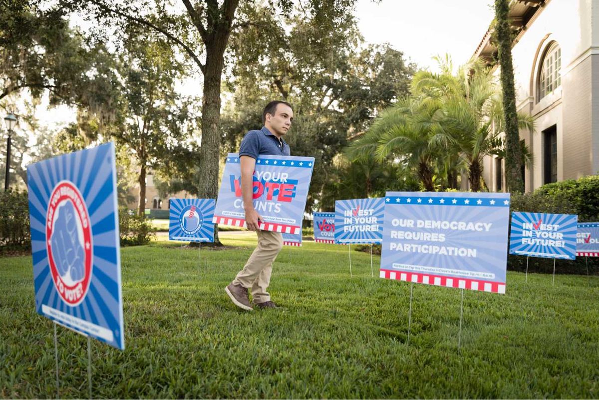 A student planting yard signs for the Democracy Project.