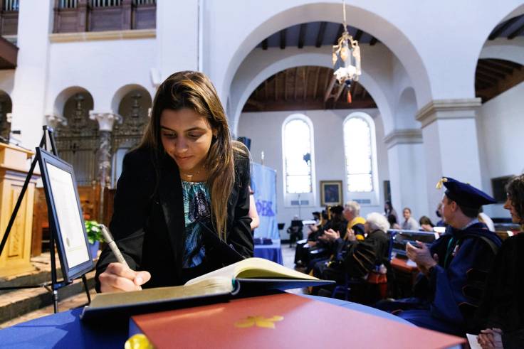 A college student signs a book during an induction ceremony at Rollins College.