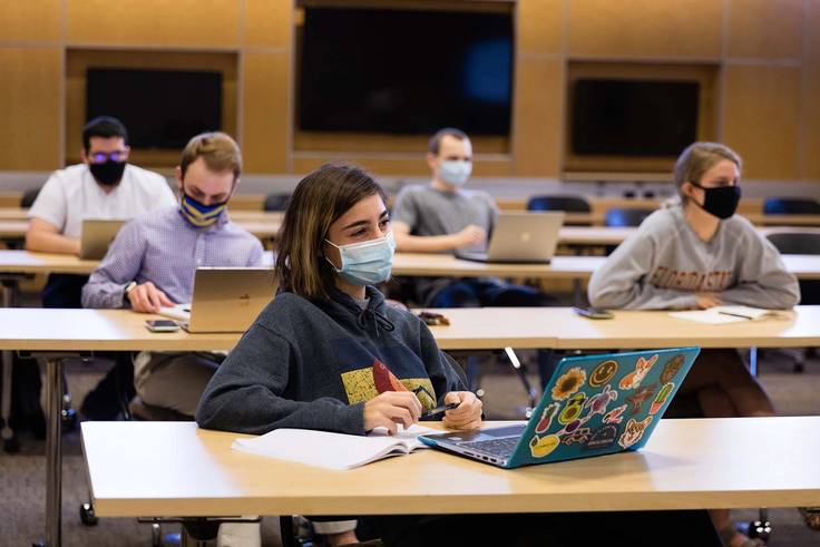 A masked student works on a laptop during an RCC class.