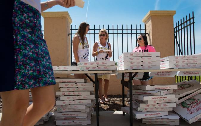 Students and staff pass out pizza from stacks of pizza boxes.