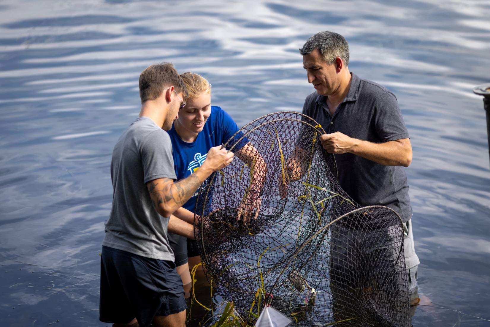 Bobby Fokidis with two students working with a net in the water