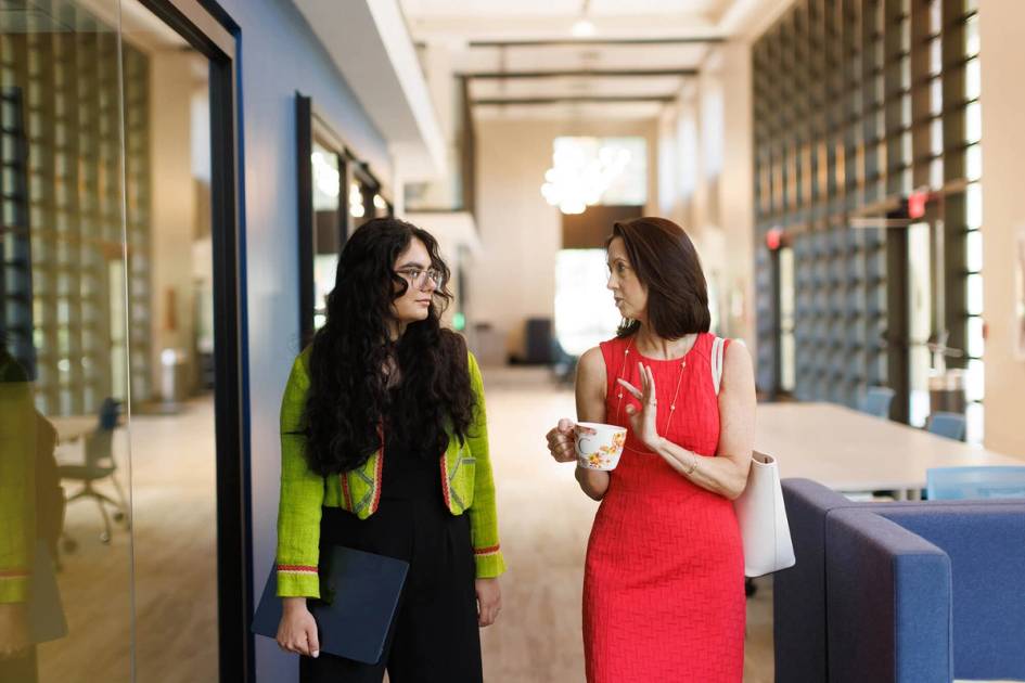 Professor and student having a discussion while walking on campus.