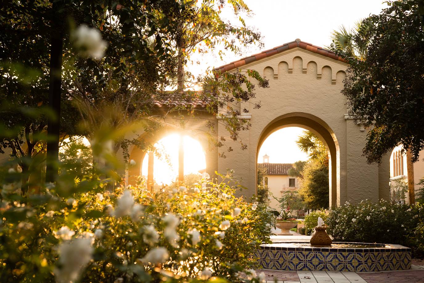 The sun rising through an archway on the Rollins Campus.