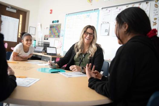 A teacher smiles as she talks with a student.