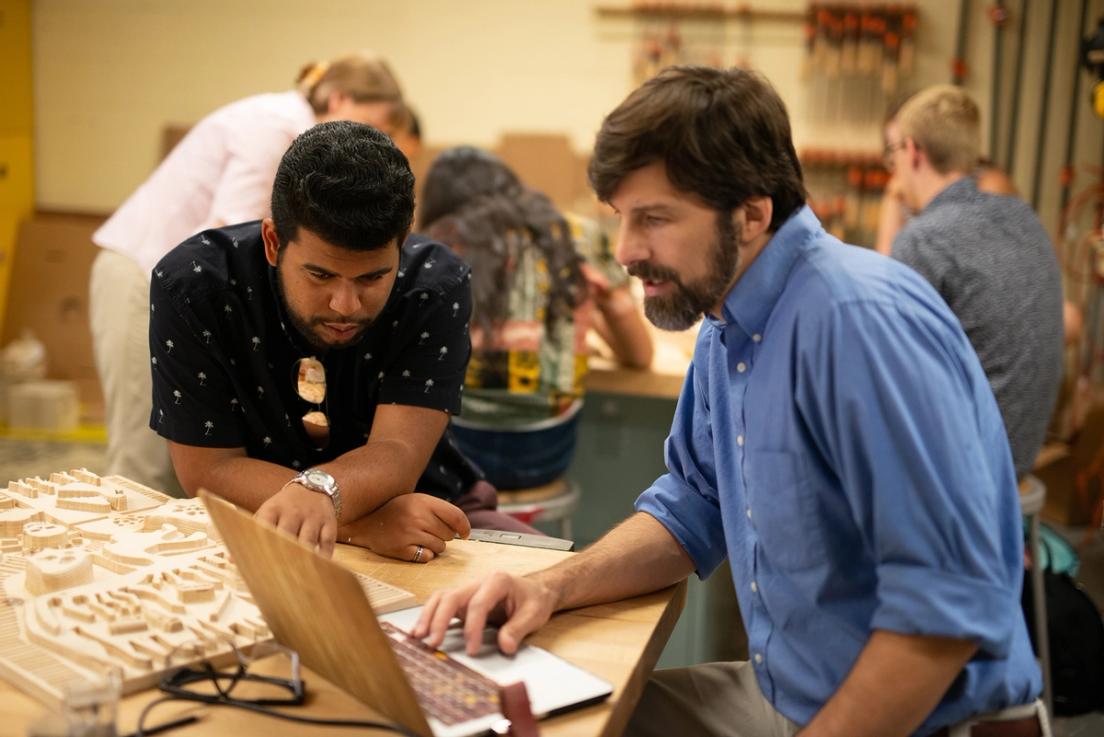 Art professor and student compare a relief to their computer models.