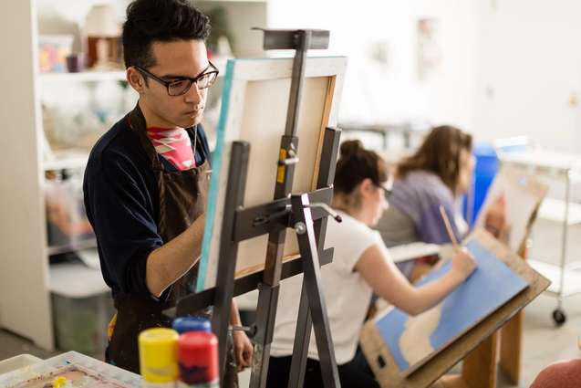 A studio art college student painting during class.