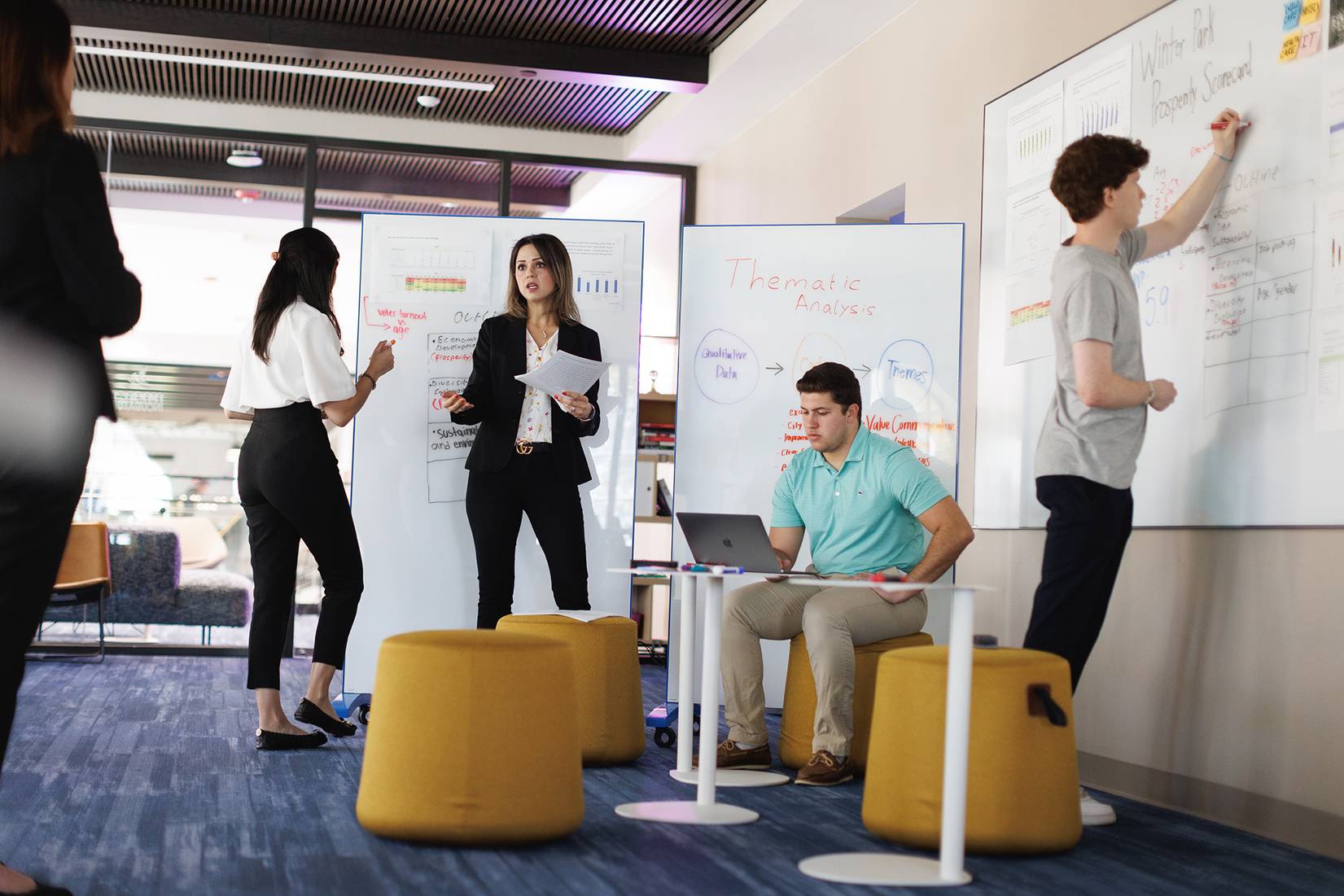 Students and professor gather in the Social Impact Hub to collaborate on a research project.