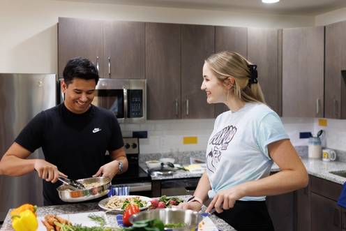 Two roommates prepare a meal kit together in their Lakeside Neighborhood dorm room.