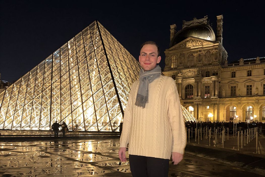 Rollins student studying in Paris, France, poses in front of the Louvre Museum.