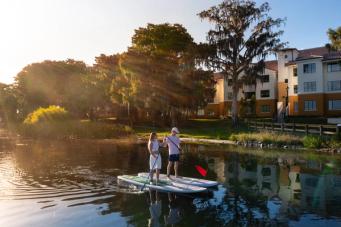 Two Rollins students paddleboarding on Lake Virginia in front of Lakeside Neighborhood