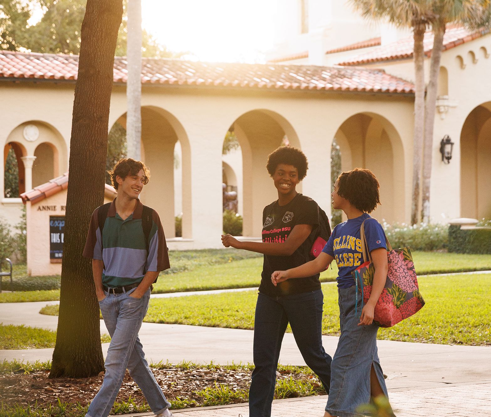 Rollins students walk and talk down a path on campus.