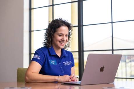 An admission counselor in a blue Rollins polo video chats with a student.