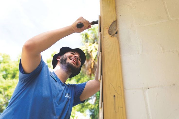 Student installing siding on a building during SPARC Day