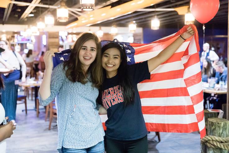 Two students pose with the American flag on the night of the 2016 presidential election results. 