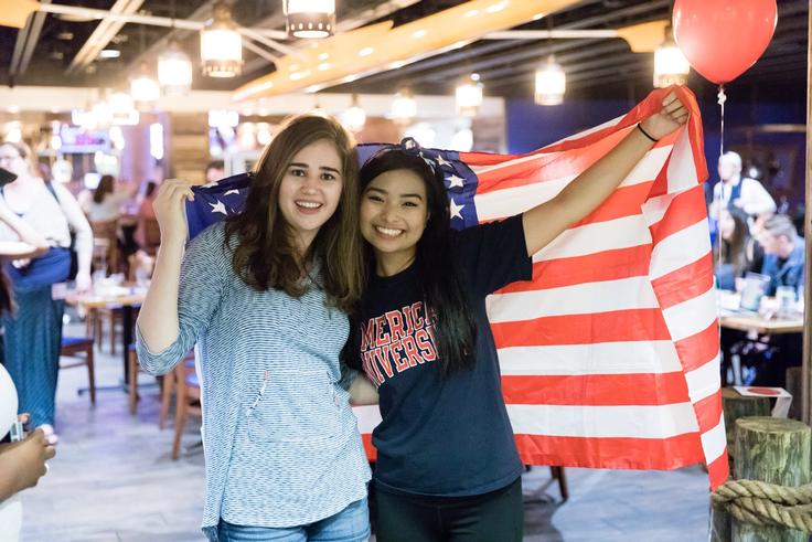 Two students pose with the American flag on the night of the 2016 presidential election results. 
