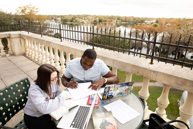 Students study together outside on the balcony of Ward Hall overlooking Lake Virginia.