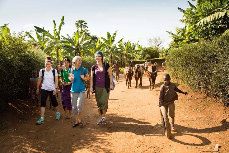 Students hike through a village in Rwanda on a field study. 